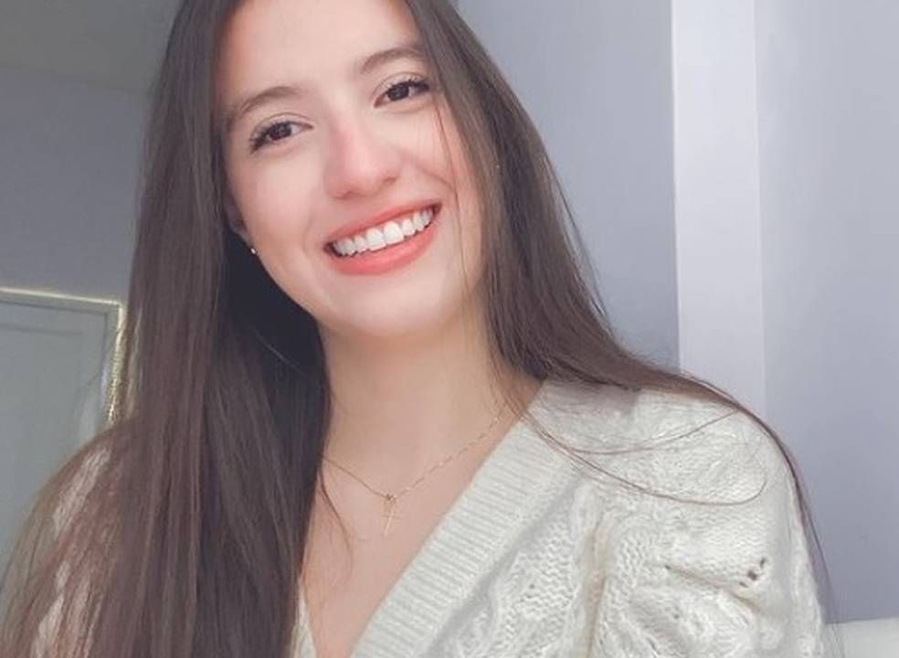 A imagem mostra a jovem estudante Luciana, que está olhando para a câmera e sorrindo