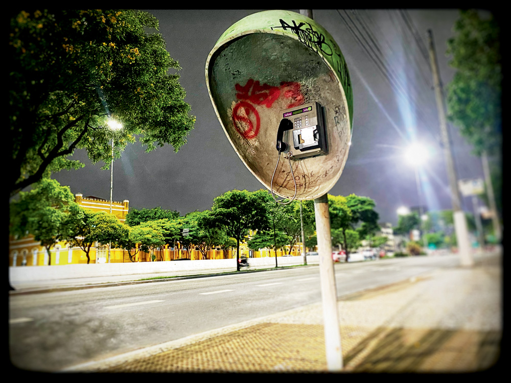 foto de orelhão vandalisado em rua deserta da cidade