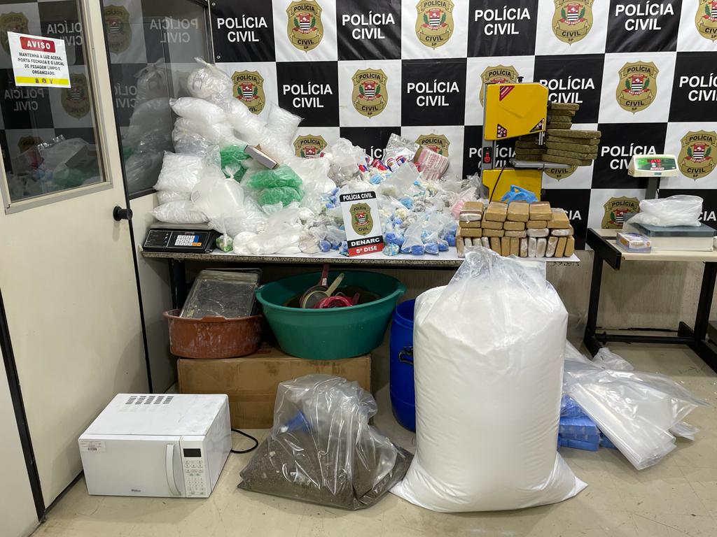 Imagem mostra fundo escrito 'Polícia Civil', com amontoado de embalagens de drogas em cima de mesa