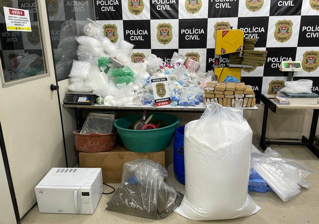 Imagem mostra fundo escrito 'Polícia Civil', com amontoado de embalagens de drogas em cima de mesa