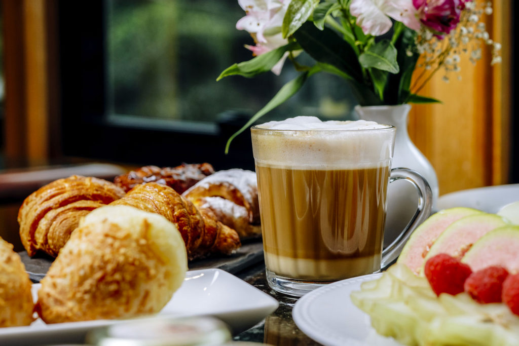 Imagem mostra café e pães variados à mesa