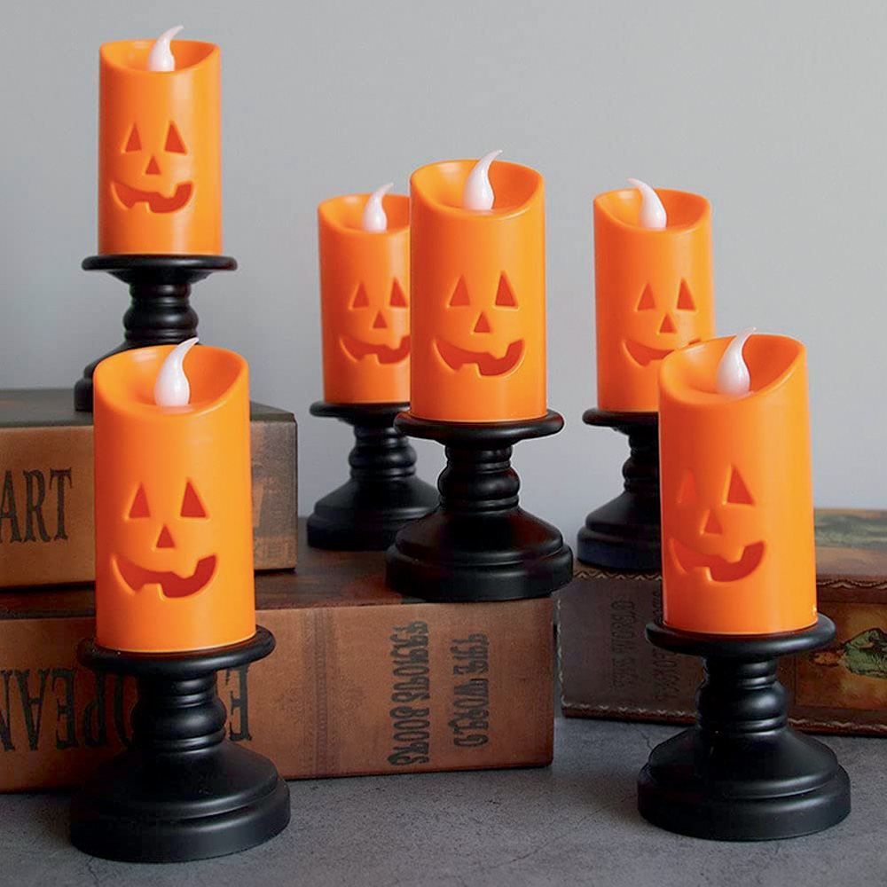 Seis velas em formato de abóbora sorrindo, de Halloween, estão dispostas em uma superfície