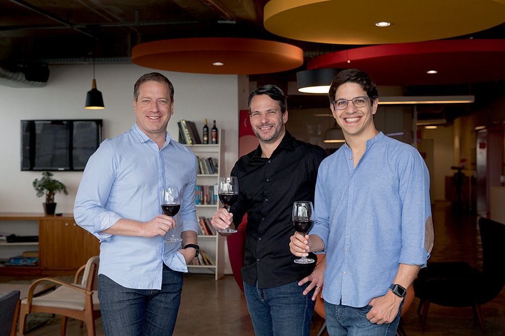 Marcos Leal (óculos), Ari Gorenstein (camisa preta) e Alexandre Bratt, posam no escritório da Evino, em São Paulo, Brasil.