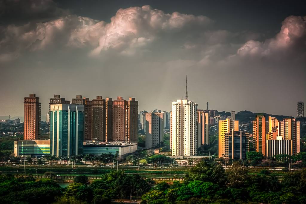 Imagem mostrando diversos prédios em São Paulo e nuvens na parte superior da imagem.