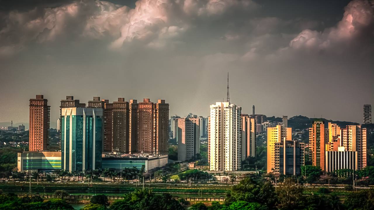 Imagem mostrando diversos prédios em São Paulo e nuvens na parte superior da imagem.
