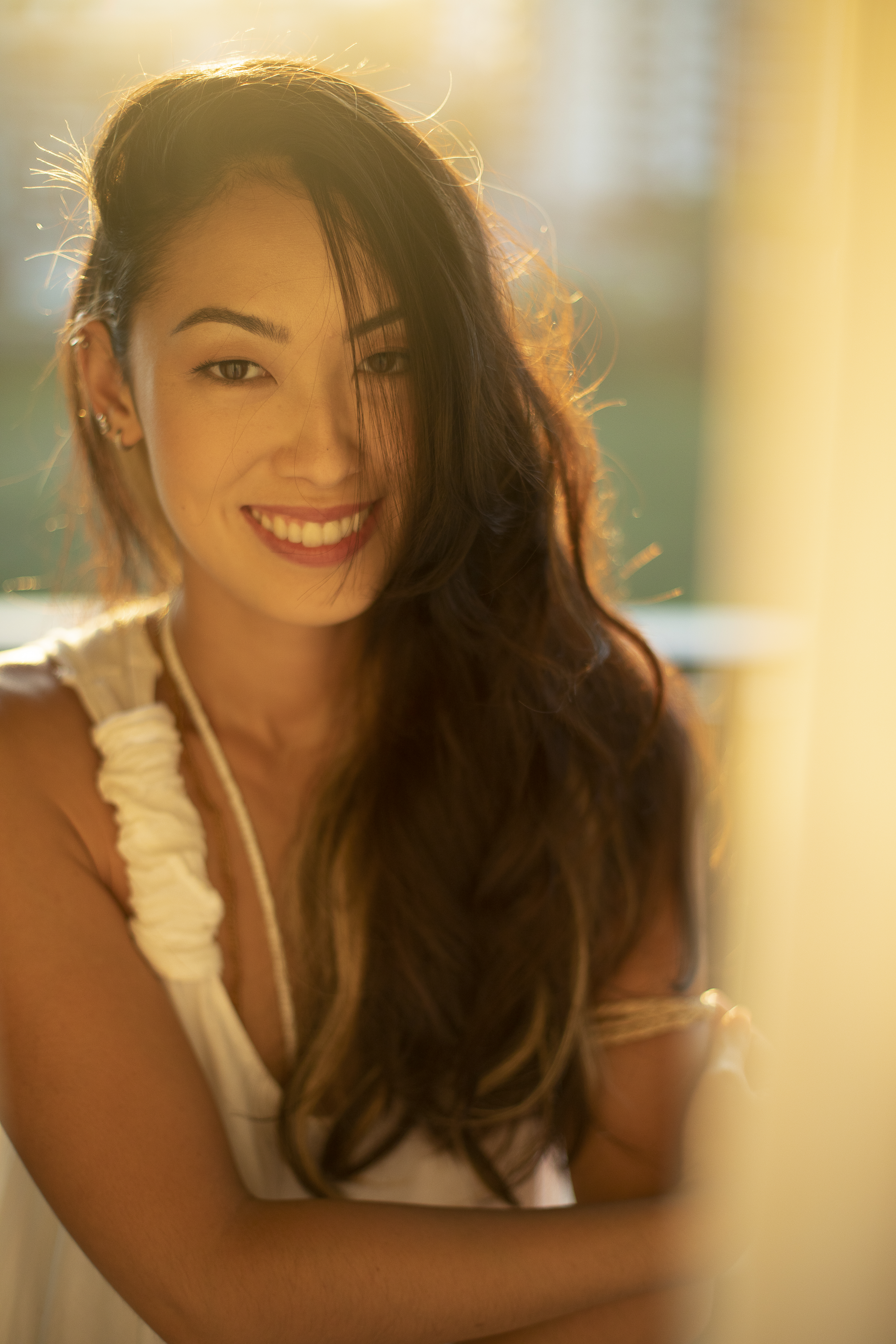 Ana Hikari sorri com parte dos cabelos escuros longos em frente ao rosto.