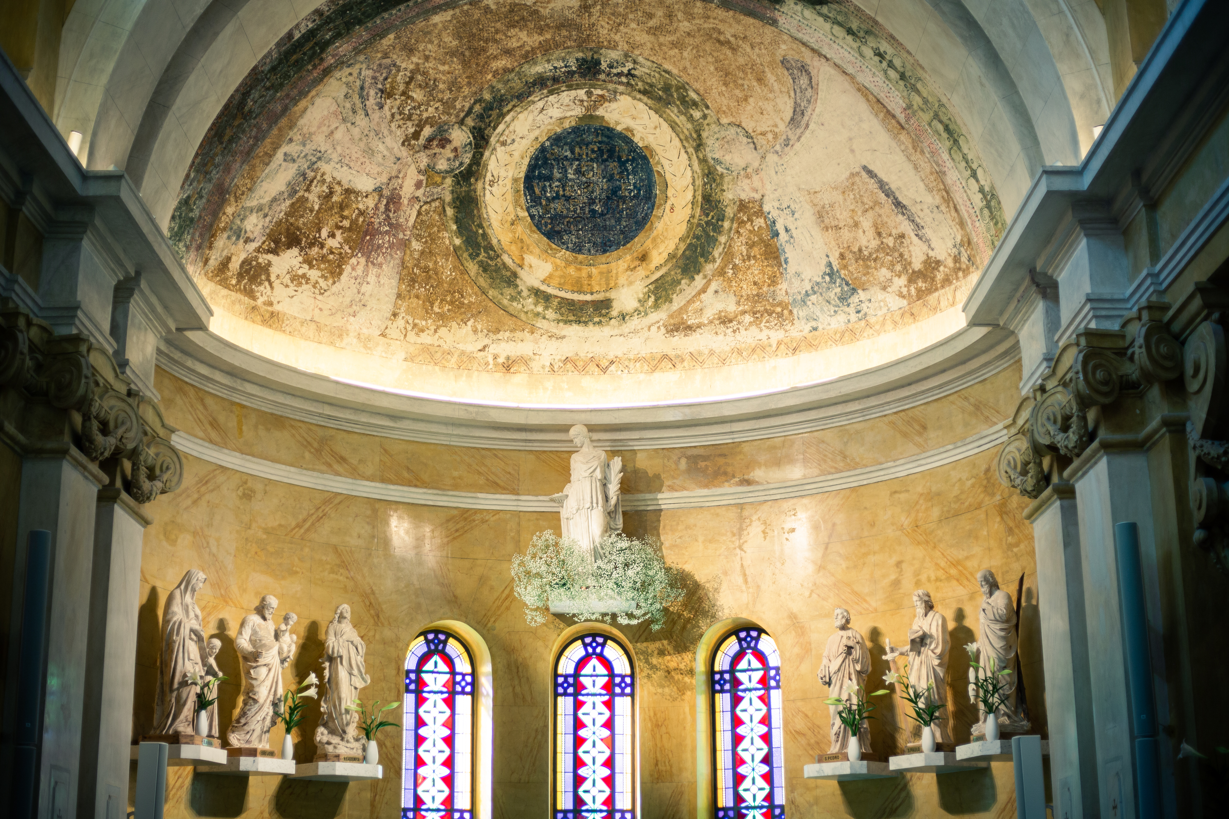 Interior da Capela Santa Luzia exibe vitrais e teto trabalhado com pinturas.