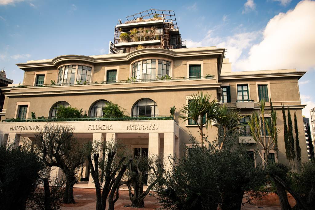 Fachada de hotel no Cidade Matarazzo com oliveiras na porta.