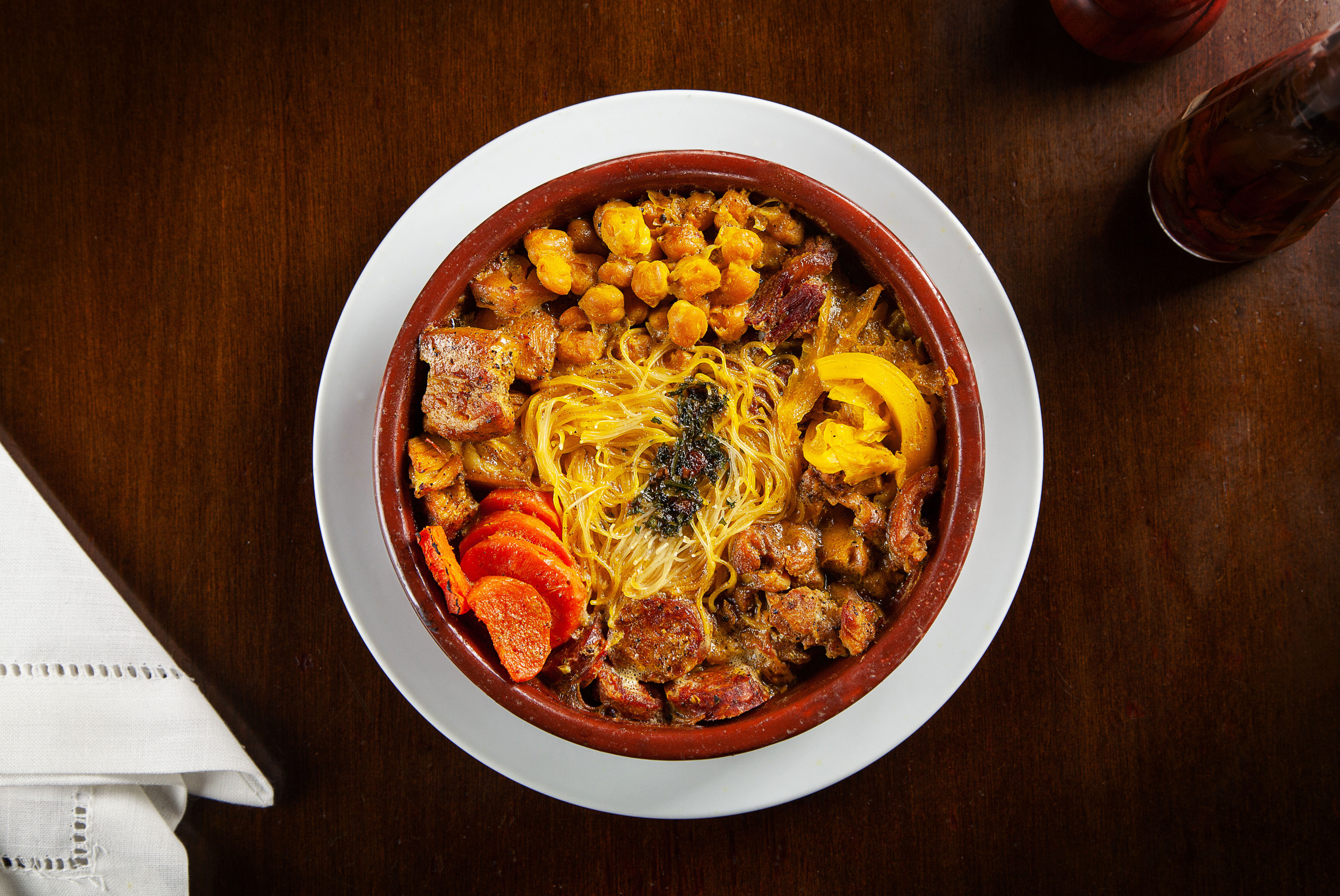 Foto aérea de cocido madrileno com carnes, cenoura, repolho, grão-de-bico e macarrão.