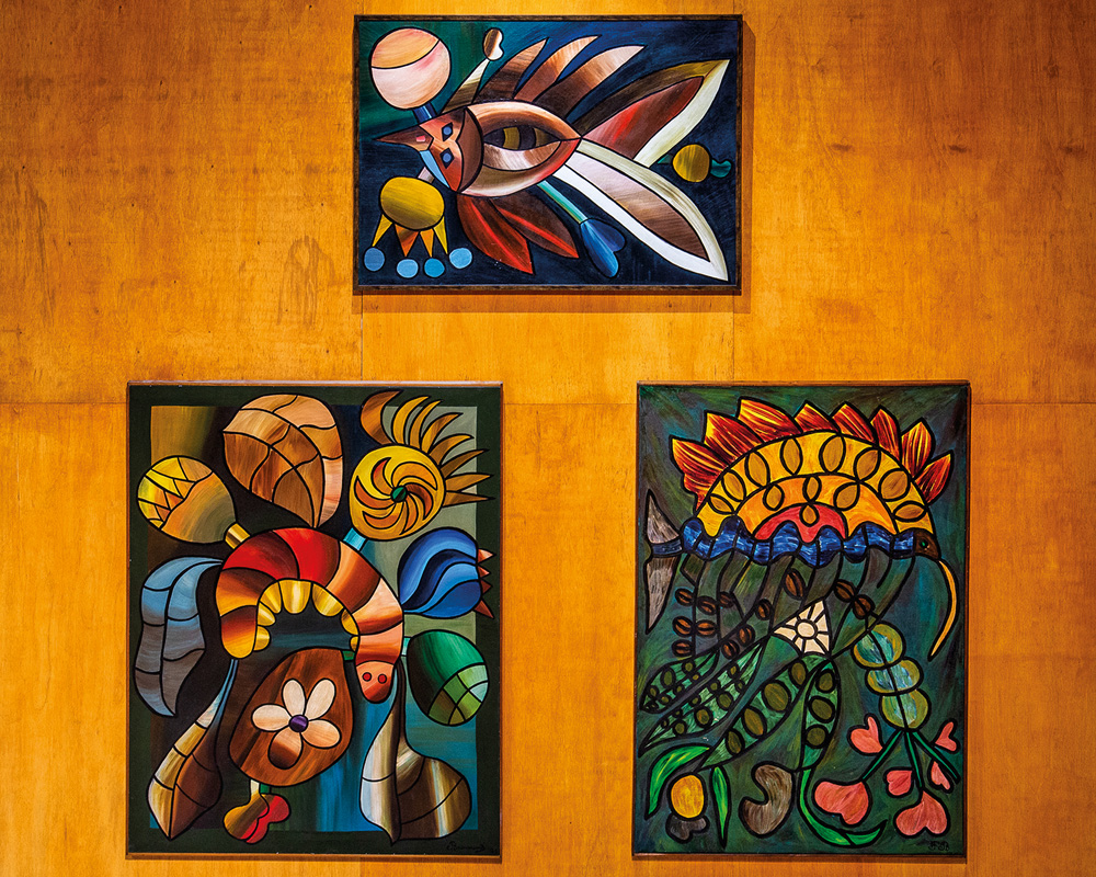 IOCFB_Credito__Breno e Gabriel Laprovitera (56).jpg (1) Imagem mostra três pinturas expostas em parede. As três são coloridas e mostram animais e plantas.