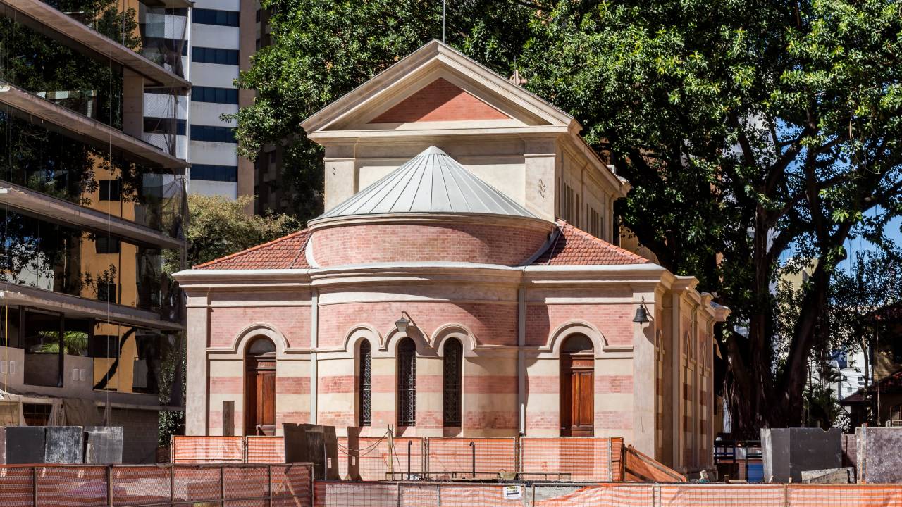 Imagem mostra parte traseira de igreja, restaurada, ainda com telas de proteção na parte térrea