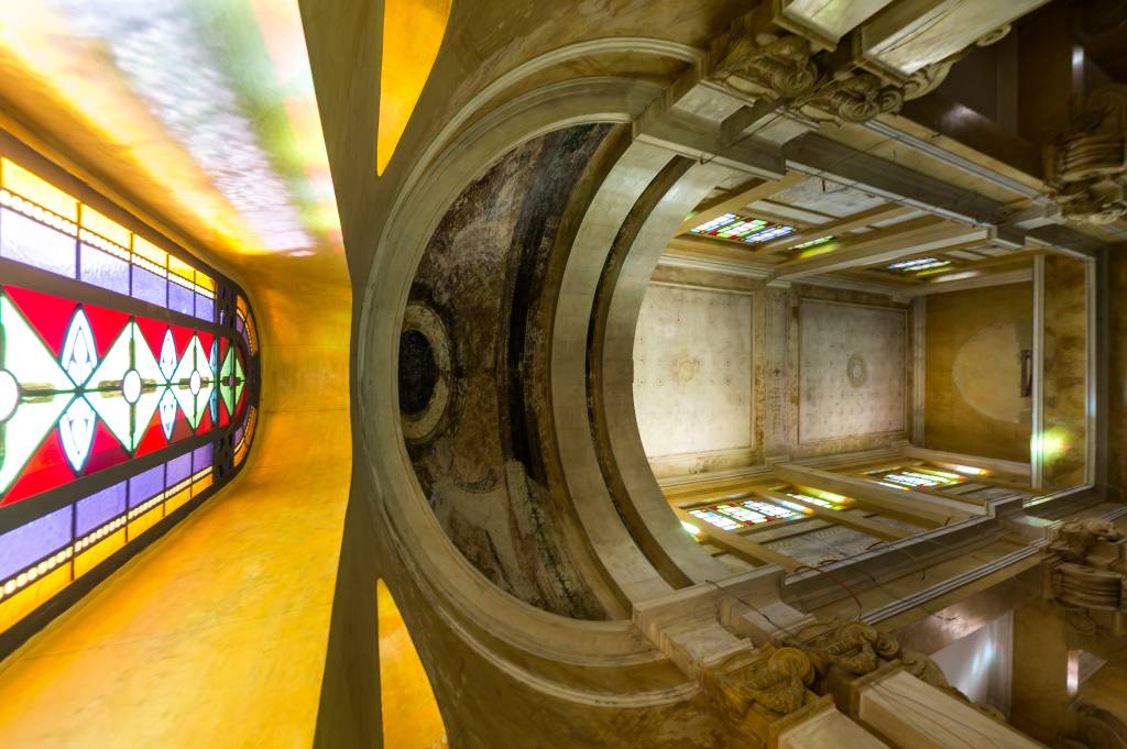 Imagem mostra interior de igreja, com teto abobadado e vitral