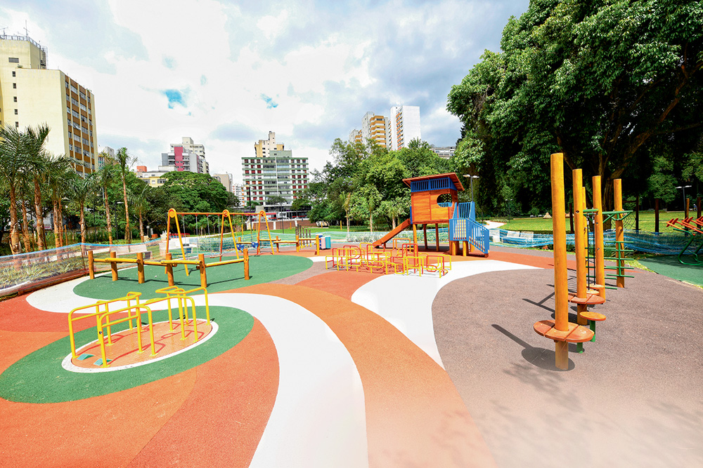 Chão laranja e branco decora espaço de exercícios com aparelhos na cor amarela em parque.
