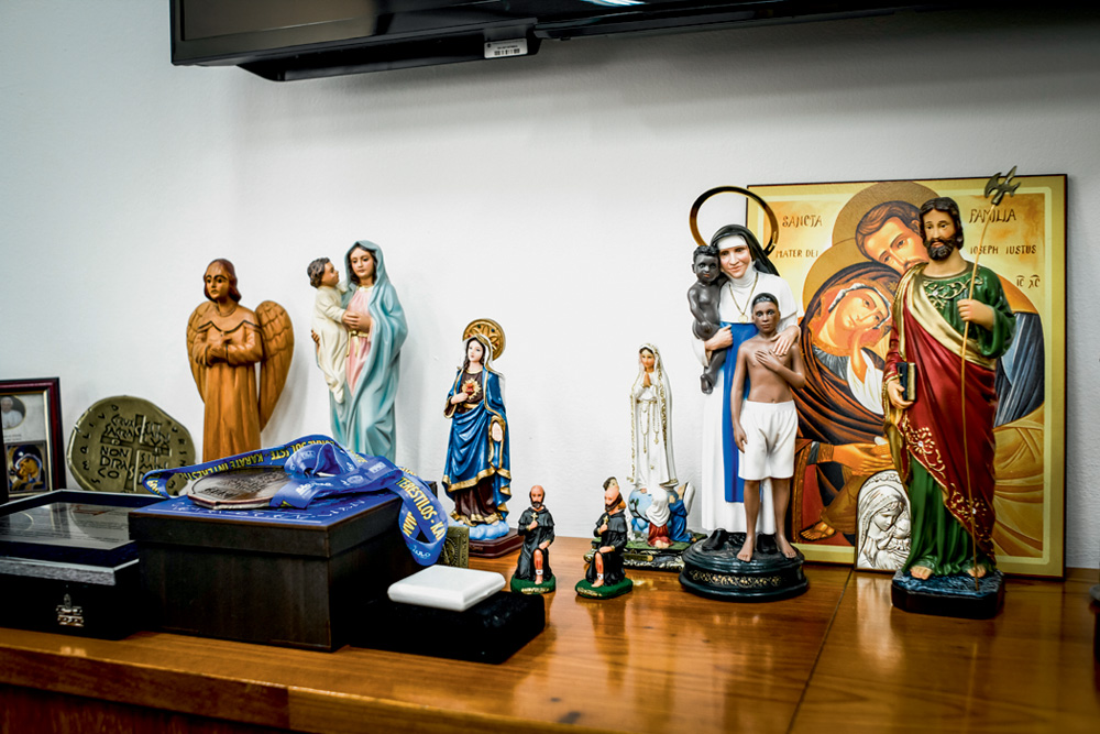 Uma mesa tem vários santos de figuras de Cristo, Maria e outros