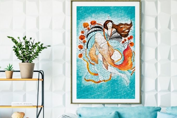 imagem de sala de estar com quebra-cabeça da obra de arte Sonho de Mar, de Eva Uviedo, monstado, enquadrado e pendurado na parede. abaixo, um sofá azul e à esquerda, uma planta em uma prateleira