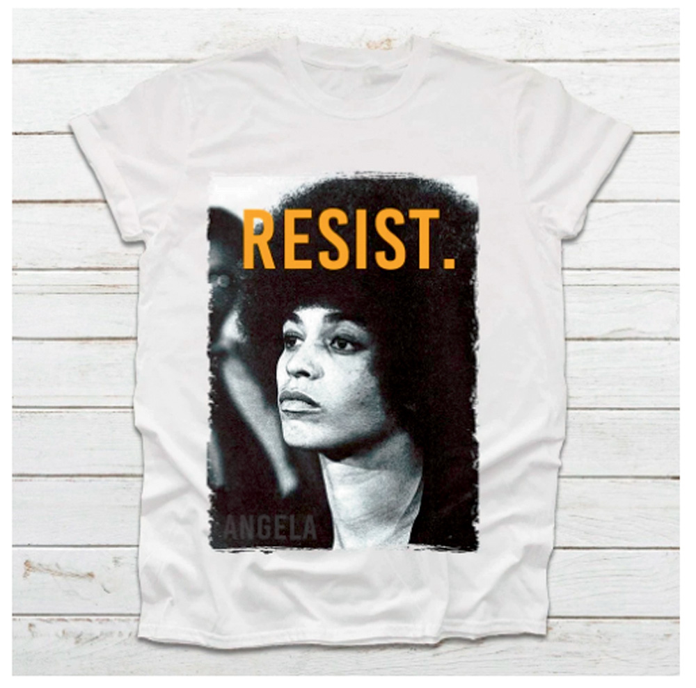Uma foto de uma camiseta branca que tem no centro um retrato retangular de Angela Davis com a palavra 