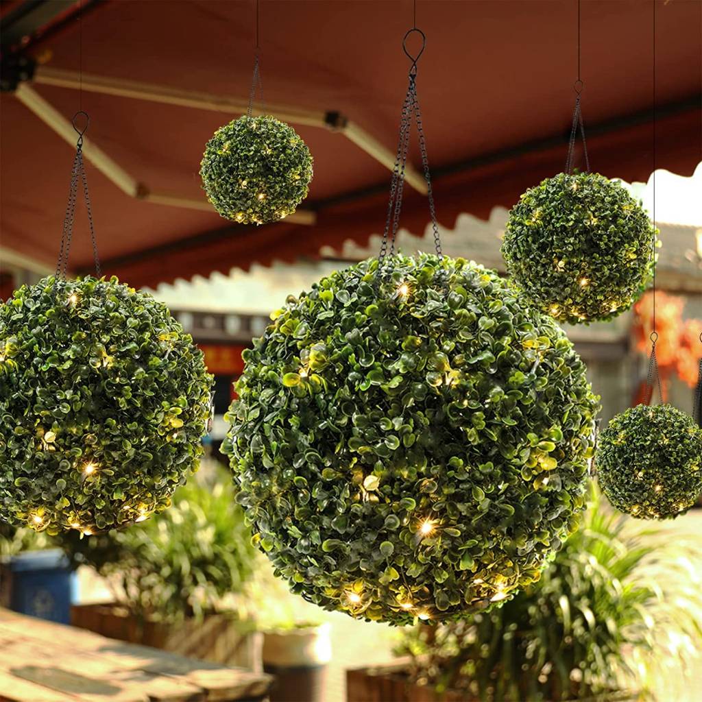 Bolas de grama penduradas no teto de um jardim tem luzes de LED entre as plantas