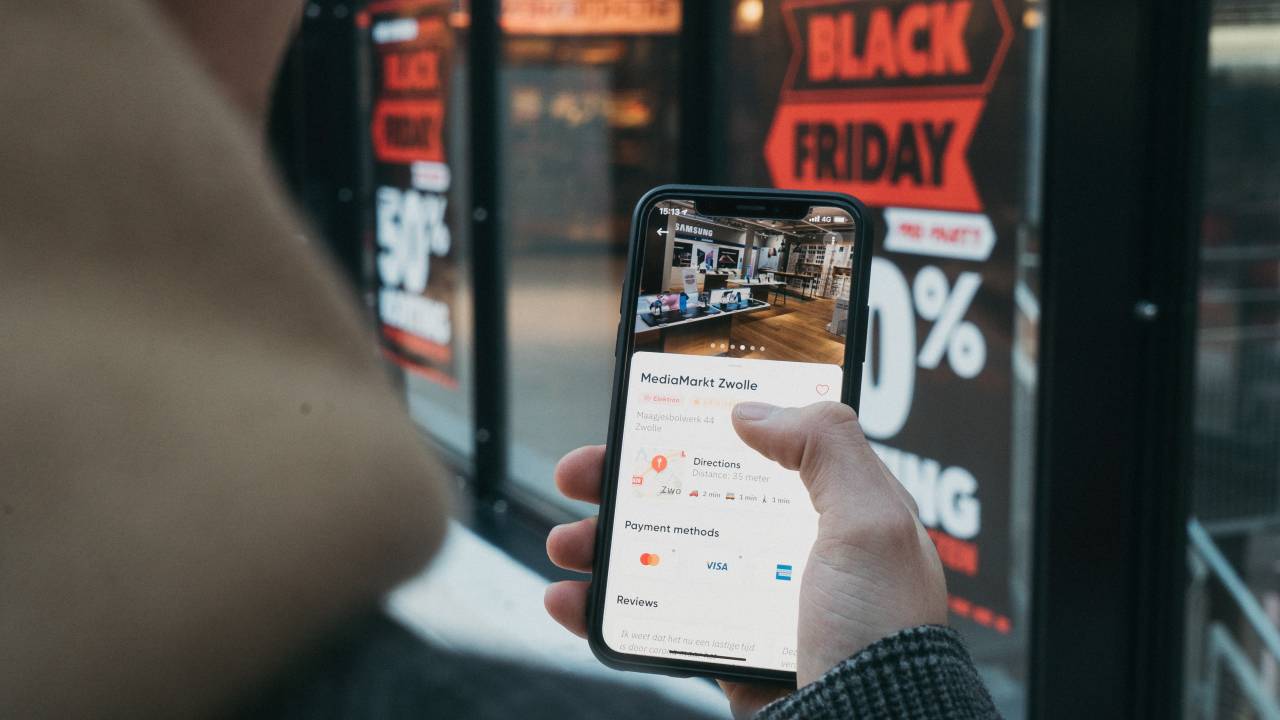 A foto mostra uma pessoa usando o celular durante jornada de compra na Black Friday