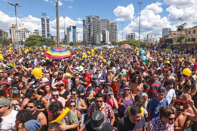 Imagem mostra uma multidão colorida de pessoas aglomeradas em um bloquinho de carnaval.