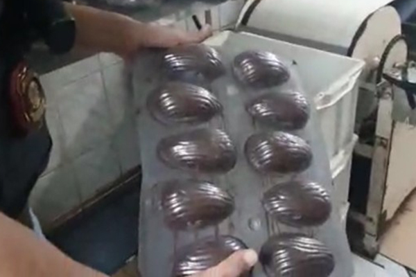 Imagem mostra policial segurando bandeja com ovos de páscoa de chocolate