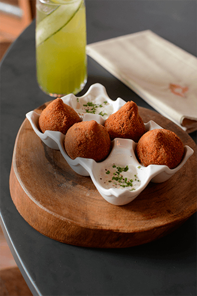 Porção de quatro coxinhas servida em cerâmica que replica uma caixa de ovos