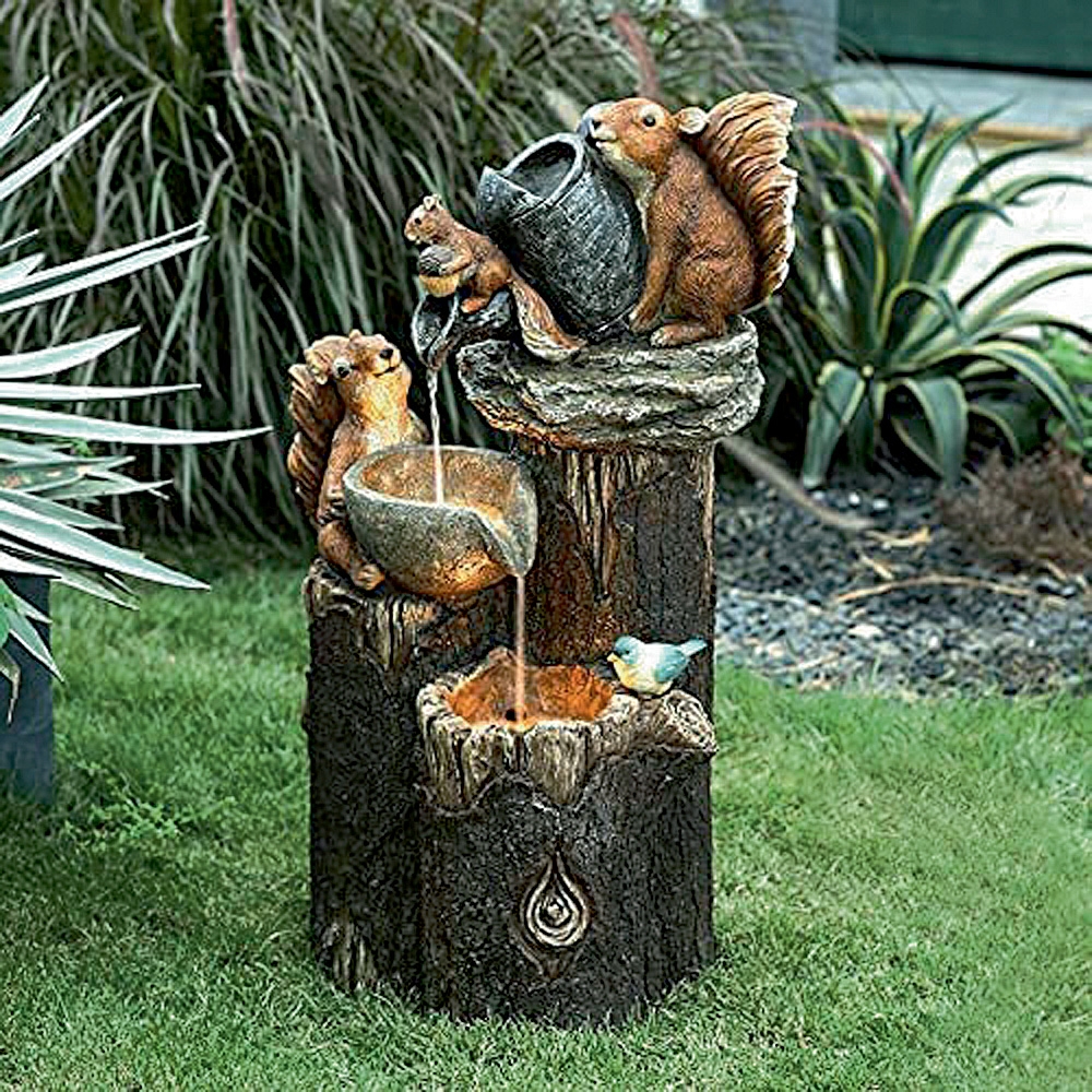 estatua2.jpg Em um jardim, há uma escultura no estilo de fonte, com água escorrendo, de um tronco e três andares. Em cada um deles, há esquilos regando o andar de baixo