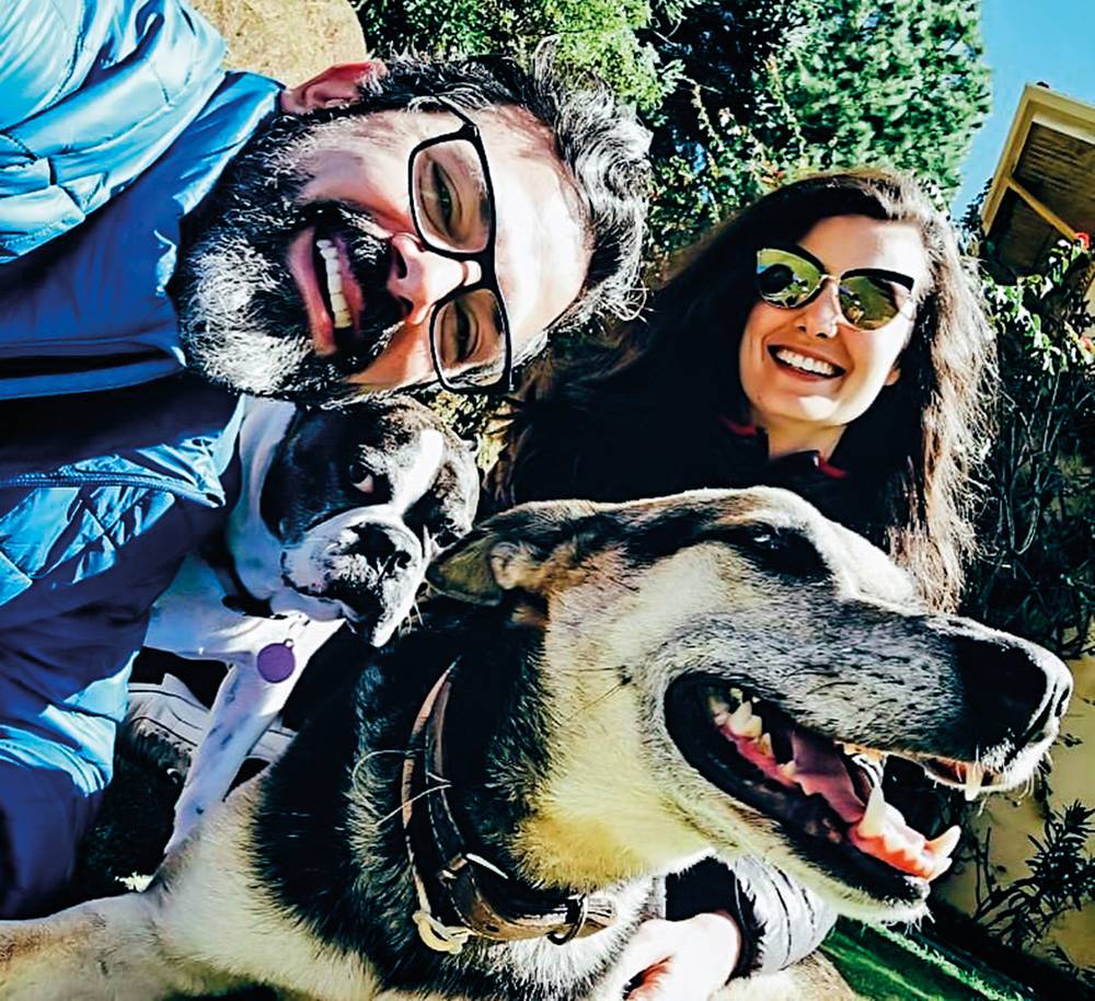 foto de baixo para cima com nathalia e erico sorrindo junto com o cachorro do casal