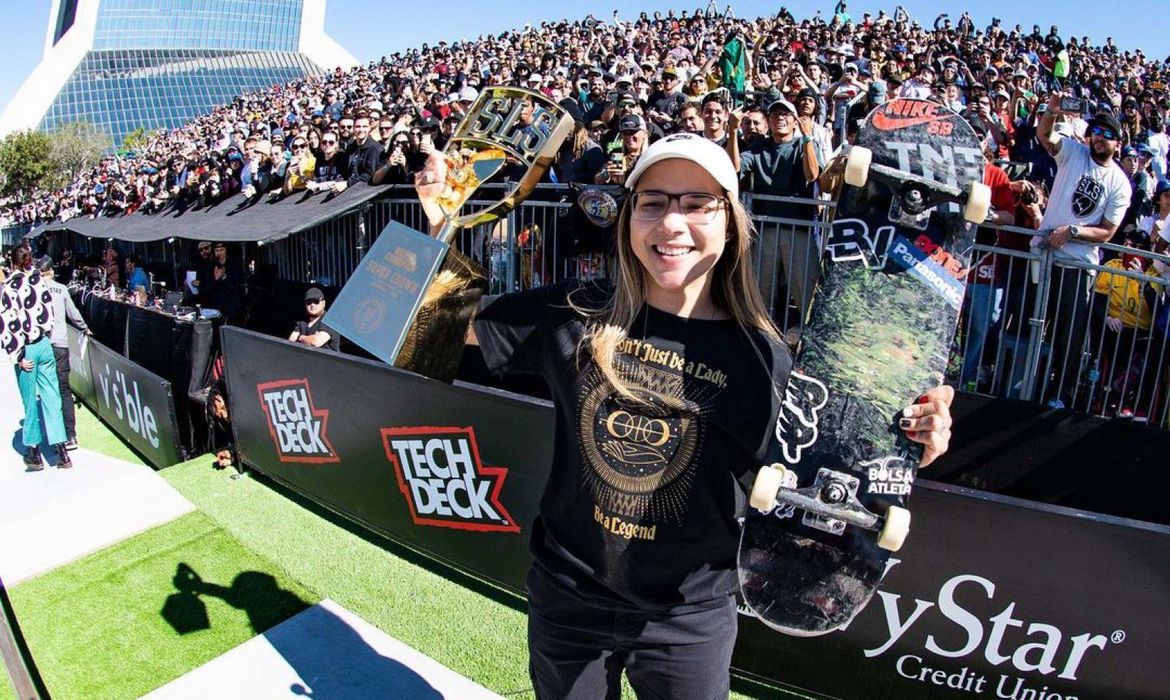Pâmela Rosa, skatista, sorri com troféu e skate na mão