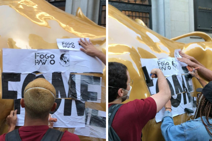 A imagem mostra grupo de jovens grudando um cartaz escrito fome em touro dourado da B3.