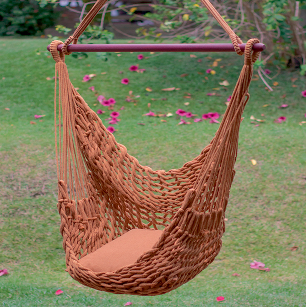 Foto mostra uma rede de cadeira estilo bordada marrom em um gramado
