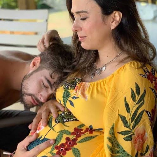 A imagem mostra Tatá abraçando o marido Rafael, que está deitado nela.