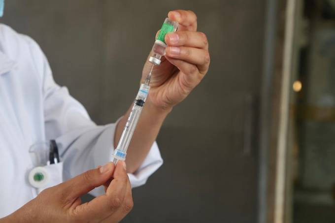 Imagem mostra pessoa manuseando seringa de aplicação de vacina.