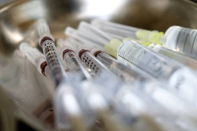 Imagem de perto mostra várias seringas de vacinação transparentes estocadas.