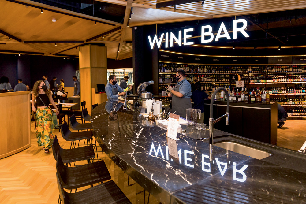 240Emporio_Shopping_Morumbi_alta.jpg Foto mostra a bancada de um bar dentro de um estabelecimento. Dá para ver dezenas de rótulos nas prateleiras