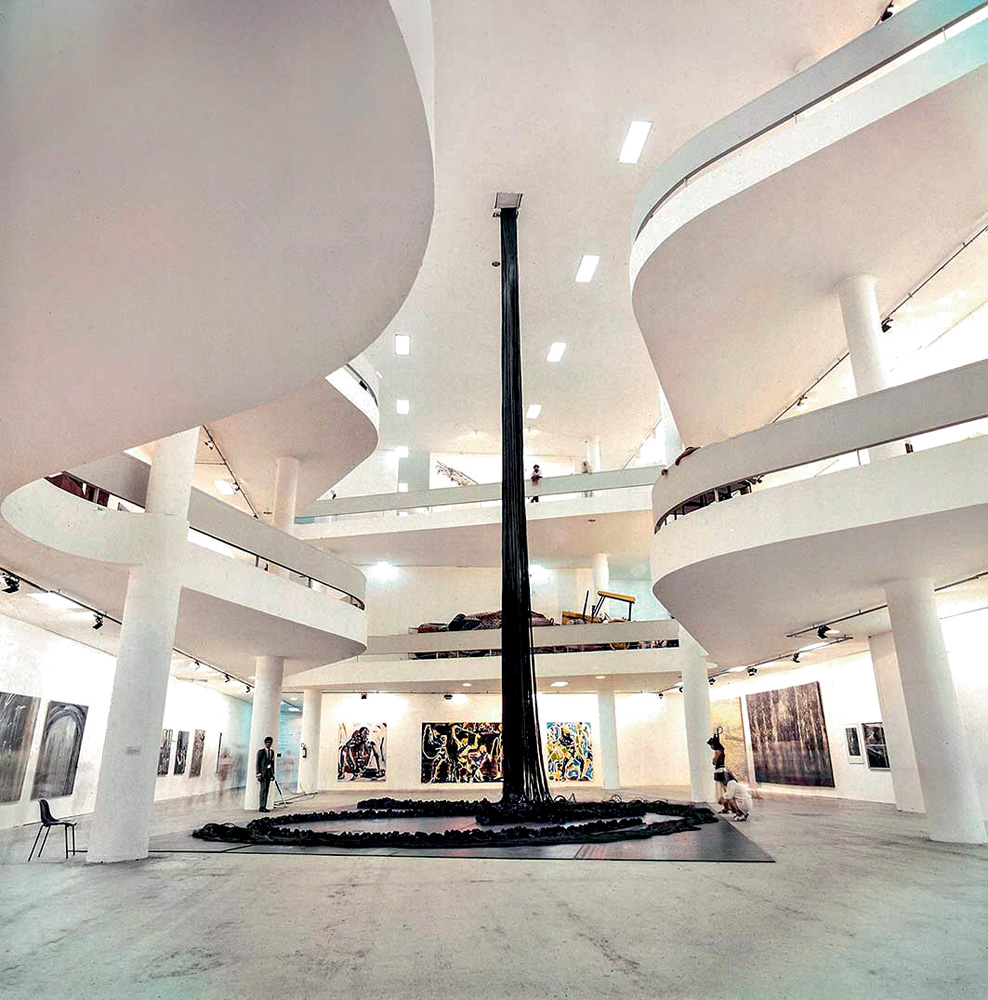 Escultura de Tunga exposta na Bienal de SP. Trata-se de uma grande estrutura em forma de paralelepípedo preto, que encontra com o teto da galeria.