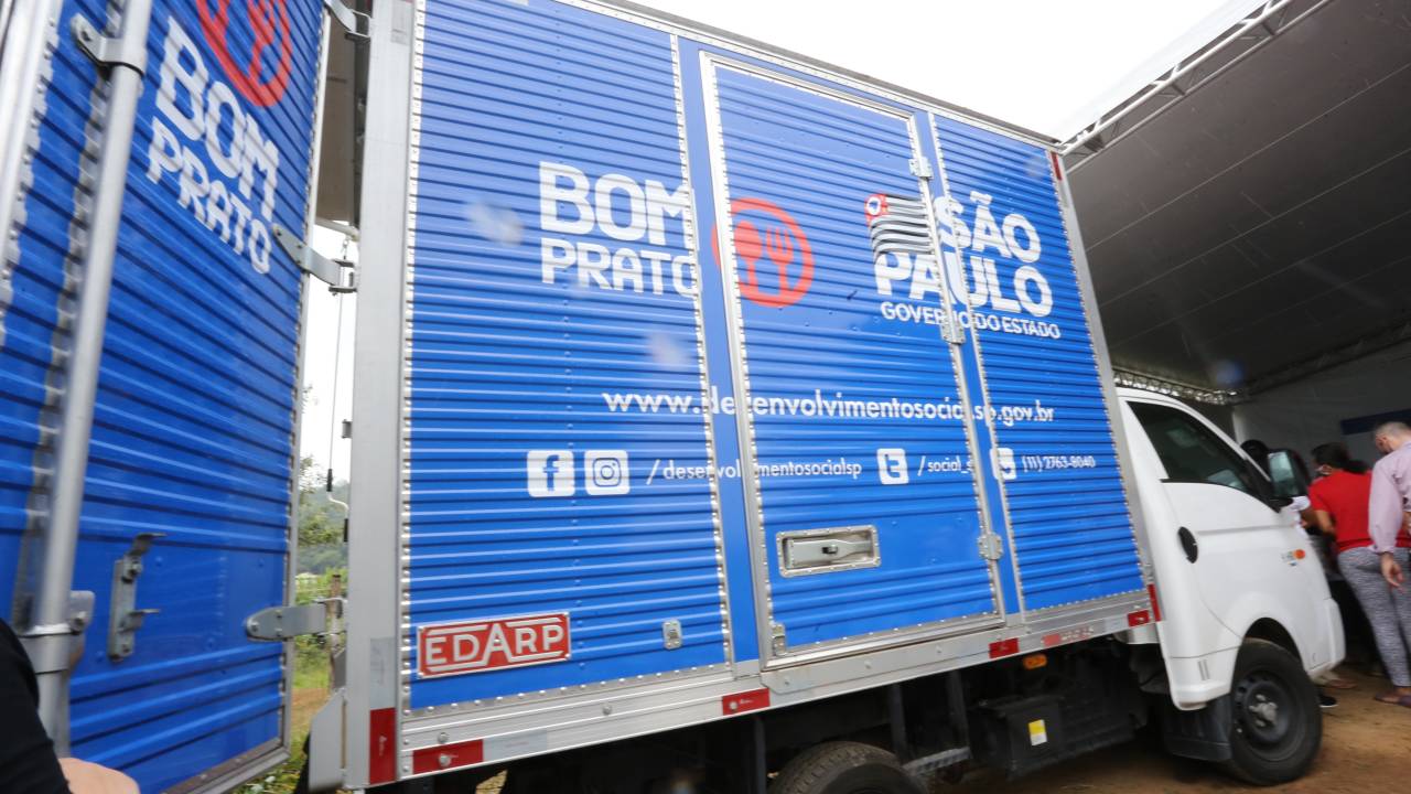 Foto de um caminhão. Laterais do contêiner do caminhão estão decoradas com logos do "Bom Prato"