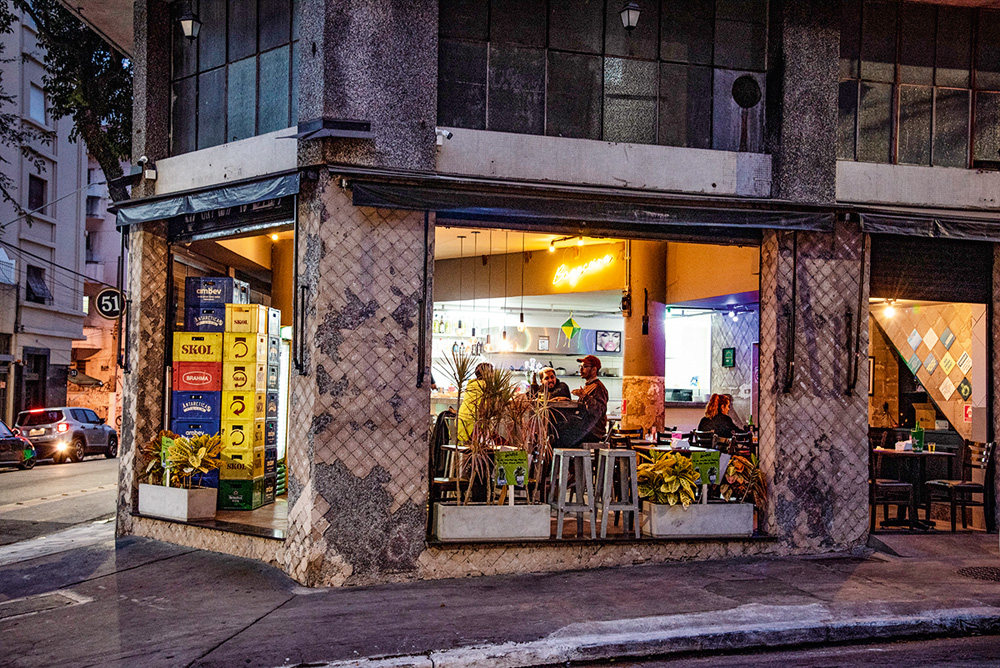 Bar aberto com banquetas e mesas visíveis a partir da visão da rua
