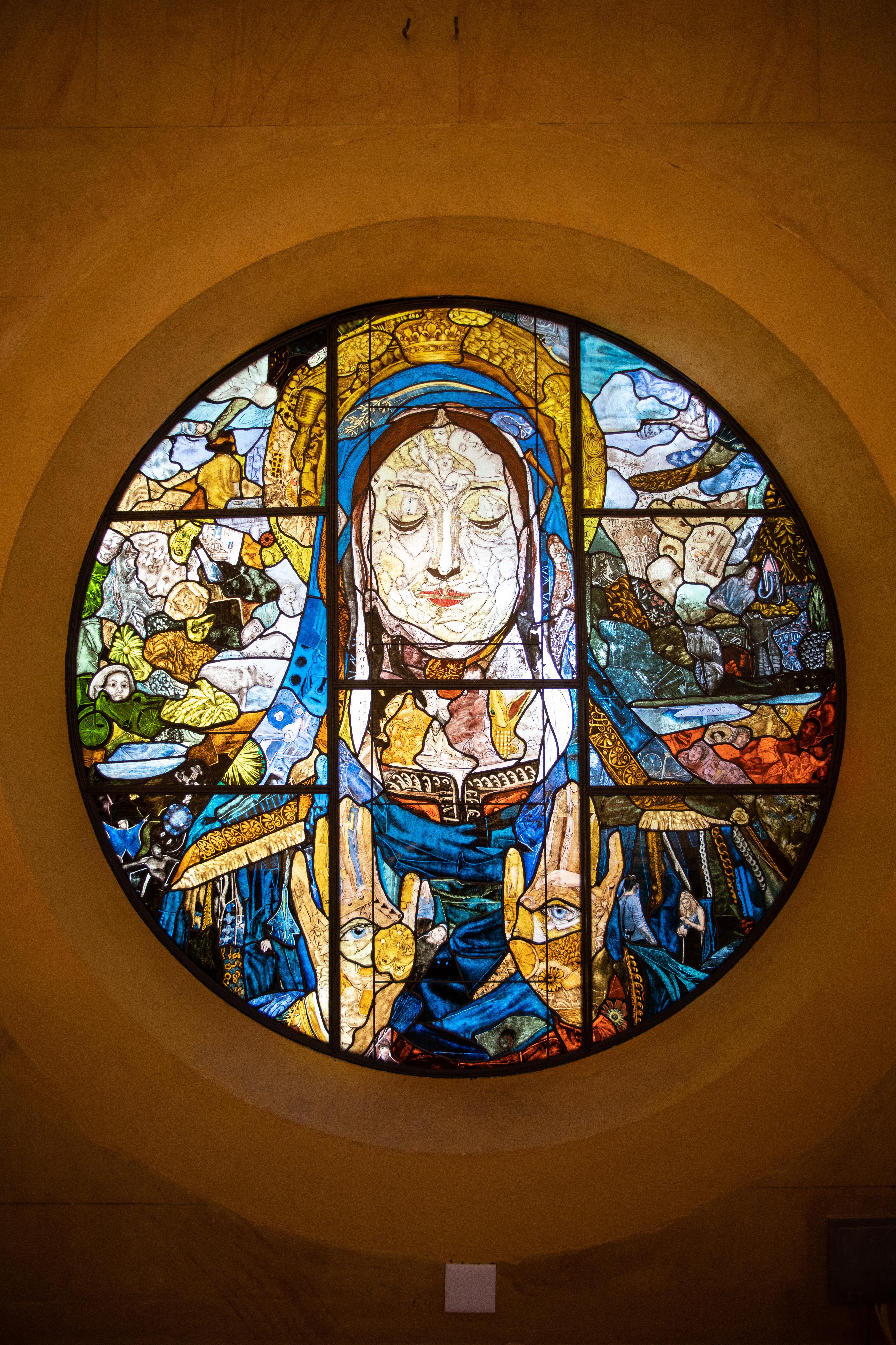 Foto mostra um vitral arredondado de uma igreja. Imagem é de Maria