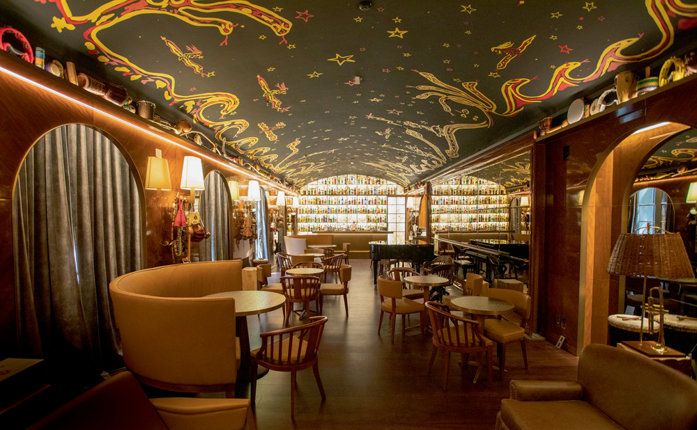 Interior do bar Rabo di Galo. Há mesas, ao fundo, um bar e o teto tem pinturas