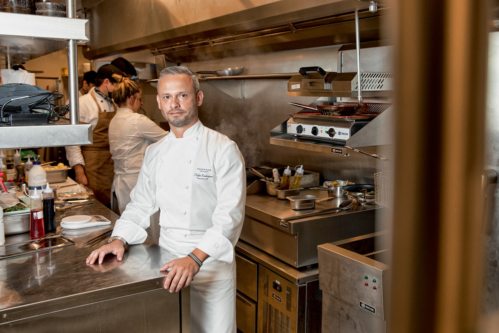 Um chef de avental posa em uma cozinha de restaurante