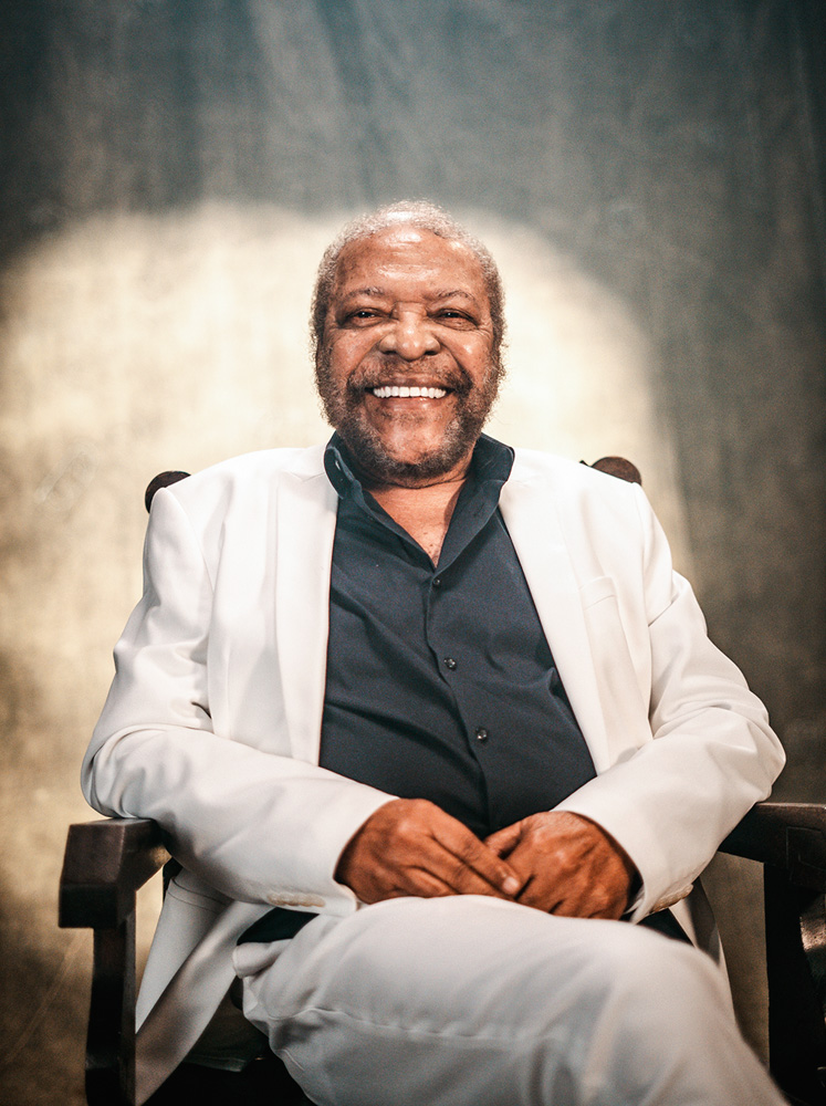 Crédito João Maia.jpg Imagem mostra homem de terno branco sorrindo, sentado em cadeira.