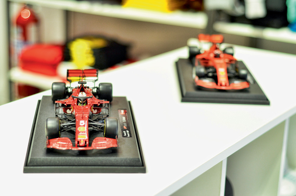 Foto mostra duas miniaturas de carros da Fórmula 1 em uma bancada branca