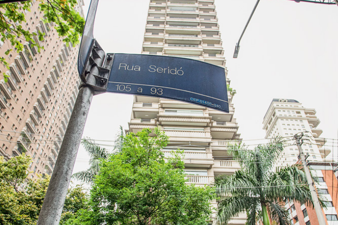 Imagem mostra placa de rua escrita "Rua Seridó" com prédios ao fundo.