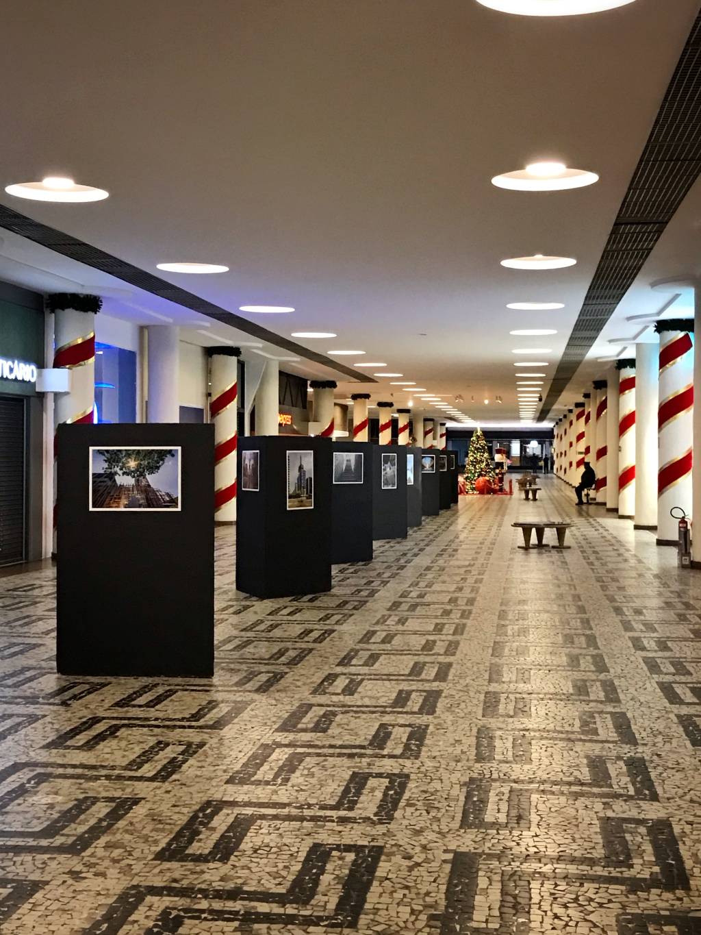Imagem mostra corredor com painéis pretos com imagens coladas.
