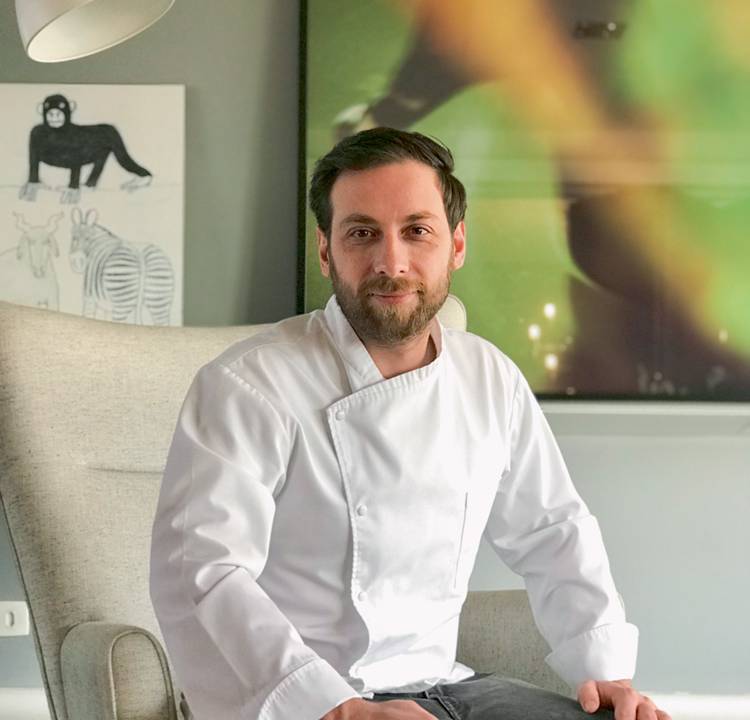 Leonardo Russi posa sentado em vestimentas de chef