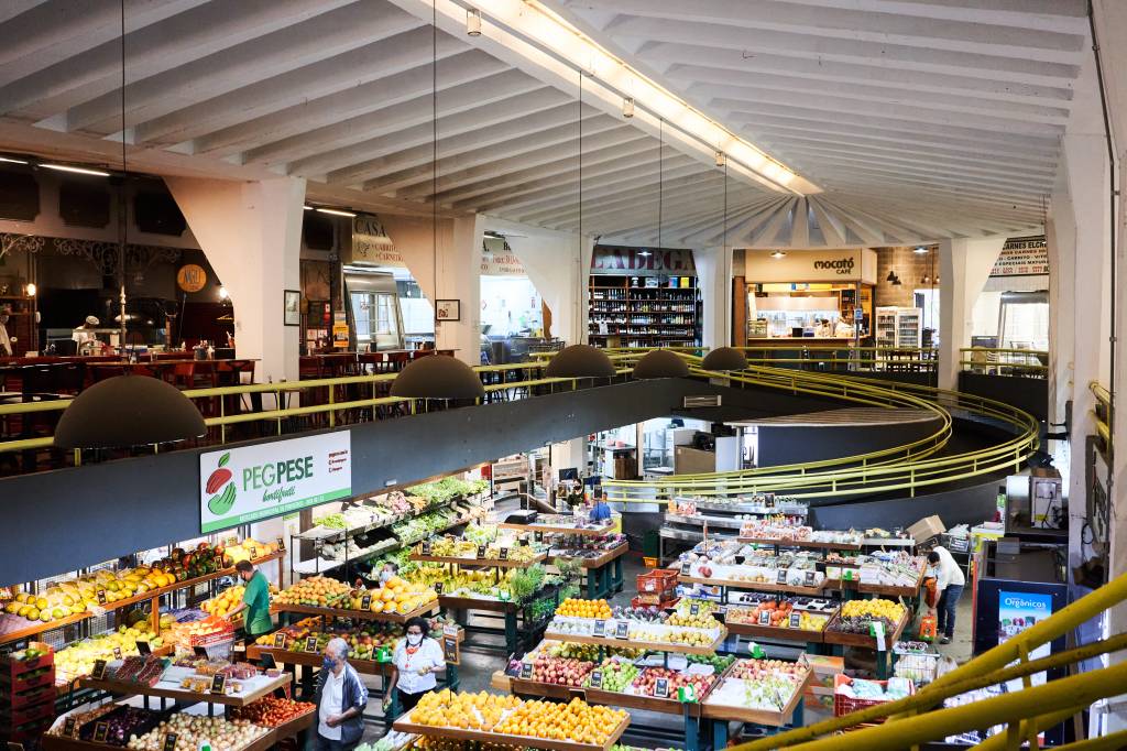 Imagem mostra mercado. com frutas e vegetais na parte inferior e um andar de cima com lojas e restaurantes