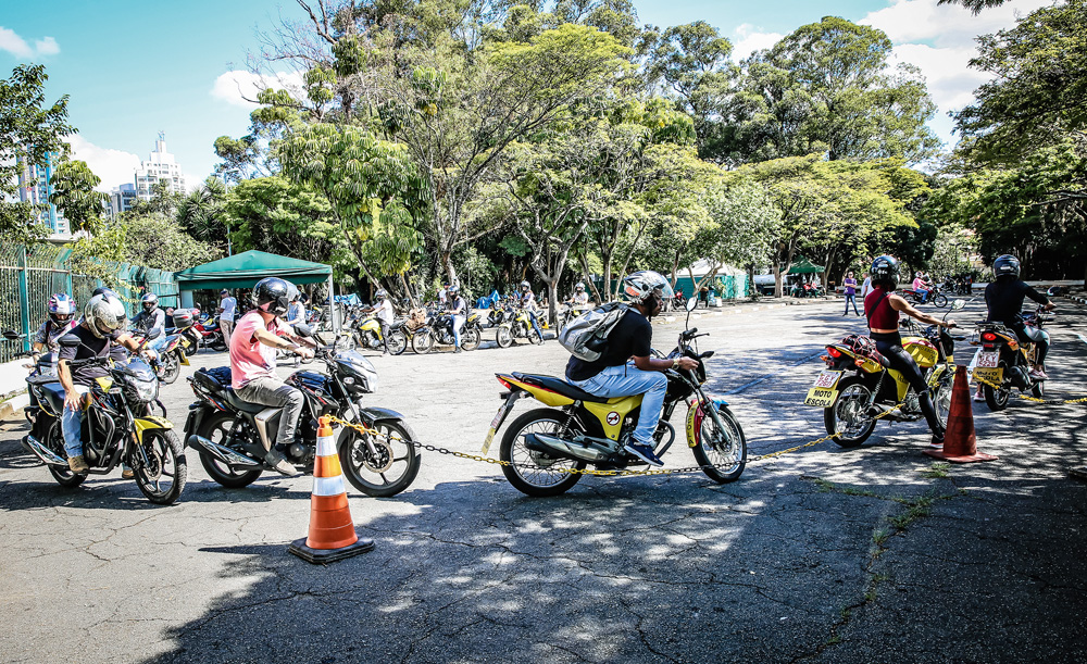 Imagem mostra diversos motociclistas em formato de círculo sobre espaço de asfalto.