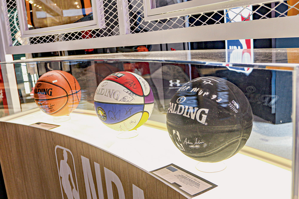 Foto mostra três bolas de basquete em uma prateleira com vidro