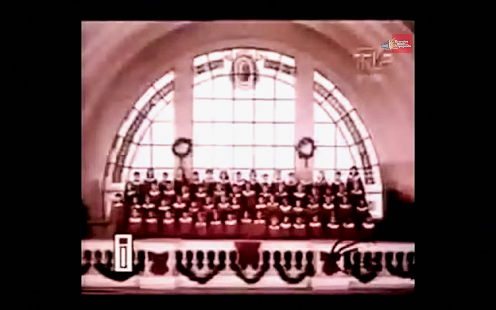 Screen Shot 2021-12-15 at 13.51.54.png Pessoas vestidas de vermelho cantam em coral para um comercial antigo do Banco Nacional.