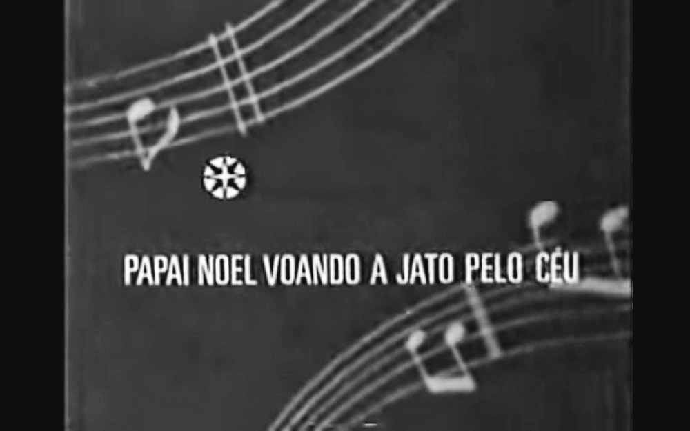 Comercial antigo mostra uma letra de uma canção natalina. A imagem, pela idade, está em preto e branco.